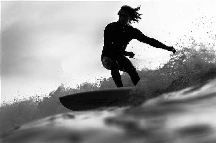 photo en niveaux de gris de l'homme sur une planche de surf